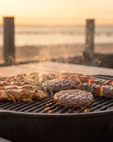 Kipsaté, hamburgers en biefstukspiesen op een houtskoolgrill, het meer onscherp op de achtergrond (AI-beeld)