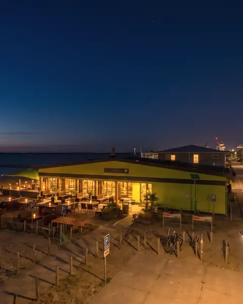 Het paviljoen 's avonds, warm verlicht aan het donkere meer (AI-beeld van een eigen foto)