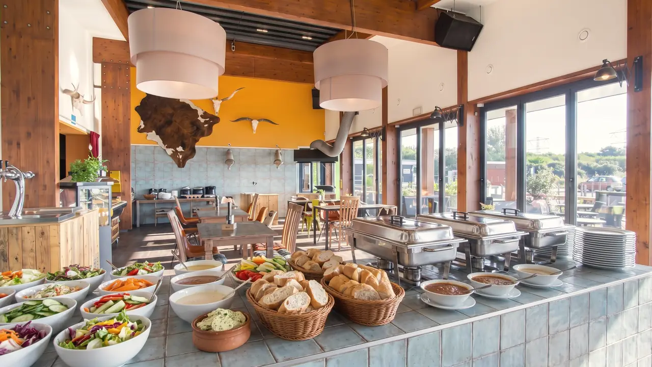 Een lunchbuffet op de toonbank in de zaal: schalen met salades, rauwkost, stokbrood en warmhoudschalen (AI-beeld)